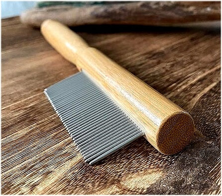 Raw Roots Steel Metal Toothed Wooden Bamboo Handled Dreadlocking Dread Comb on wooden surface with teeth closest
