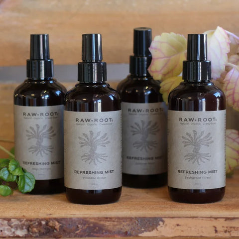 The full range of 200ml (100% recycled) bottles of RAW ROOTs Refreshing Dreadlock Deodorising Mist Sprays (Enchanted Forest, Nag Champa, Paradise Beach, and Summer Moon) shown in a natural earthy type setting
