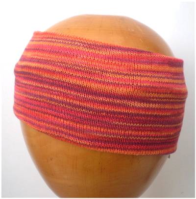 A Dreadz Fair Trade Multi-Coloured Striped Headband in Orange colours on a wooden mannequin head
