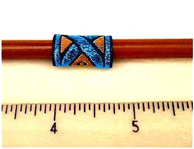 Dreadz Black, Blue and Orange patterned Dreadlock Fabric Hair Cuff, code #3533, measuring 3 quarters of and inch long by half an inch wide, shown on brown wooden knitting needle behind transparent rule demonstrating length
